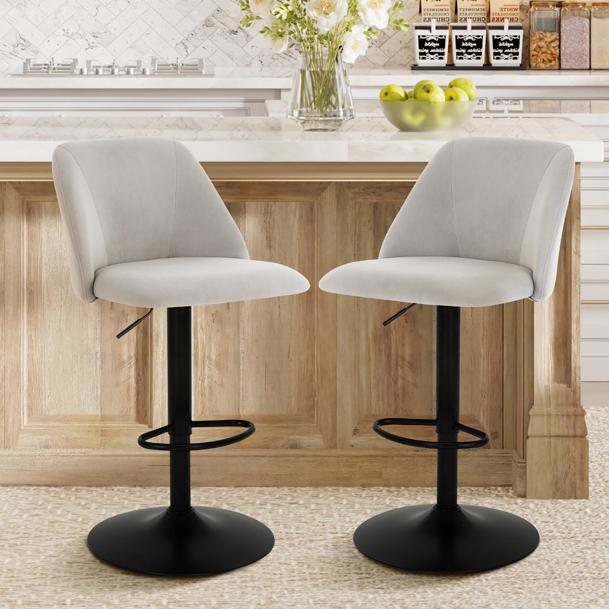 Close-up front view of two light-gray fabric swivel bar stools showing seat shape and circular footrests.