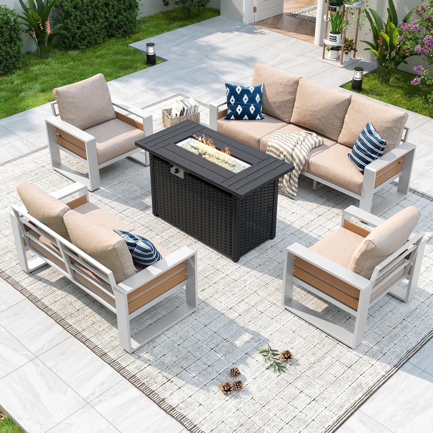 Top-down view of beige-cushioned outdoor seating arranged around a burning rectangular fire-pit table.