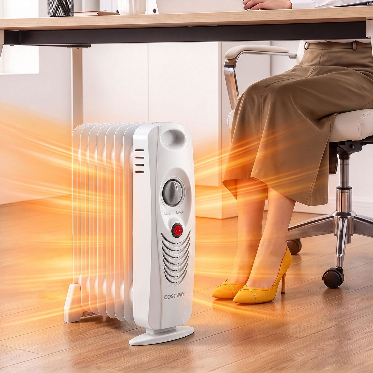 White oil-filled radiator heater beside a desk, with a seated person nearby.