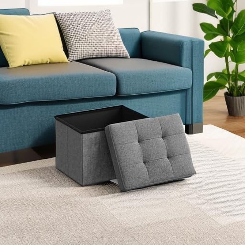 Dark gray ottoman placed on a rug beside a blue sofa with the lid set in front showing living room setting