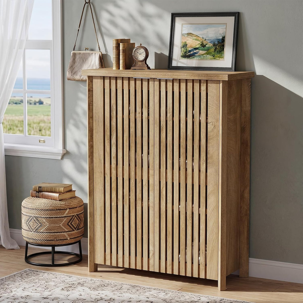 Full view of tall slatted wood shoe cabinet styled with decor in a sunlit room next to a window