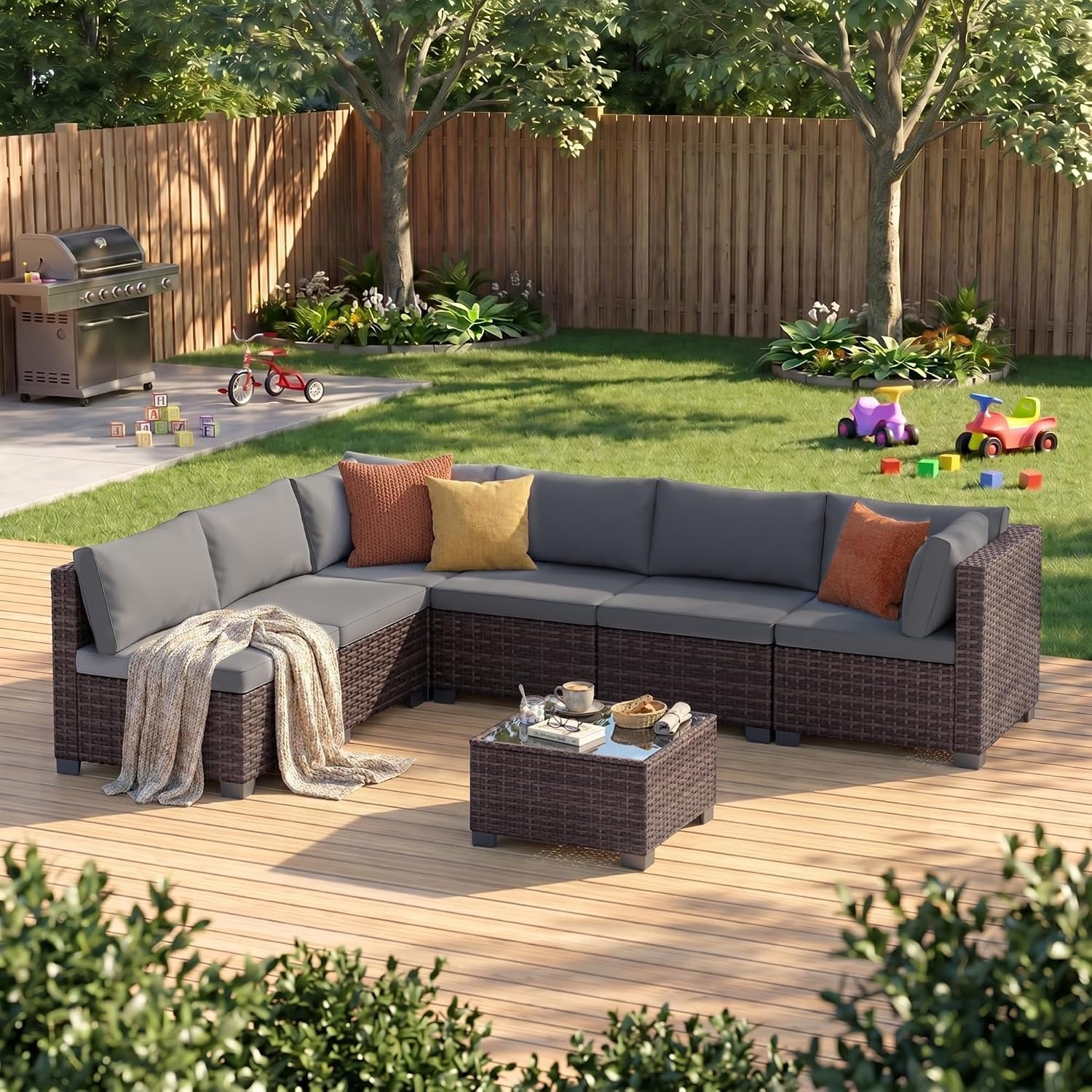 Outdoor L-shaped rattan sectional with gray cushions and a small glass-top coffee table on a wooden deck.