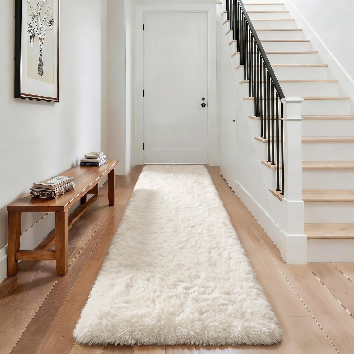 Narrow entry with fluffy cream runner, simple wooden bench on the left and white staircase with dark balusters on the right.