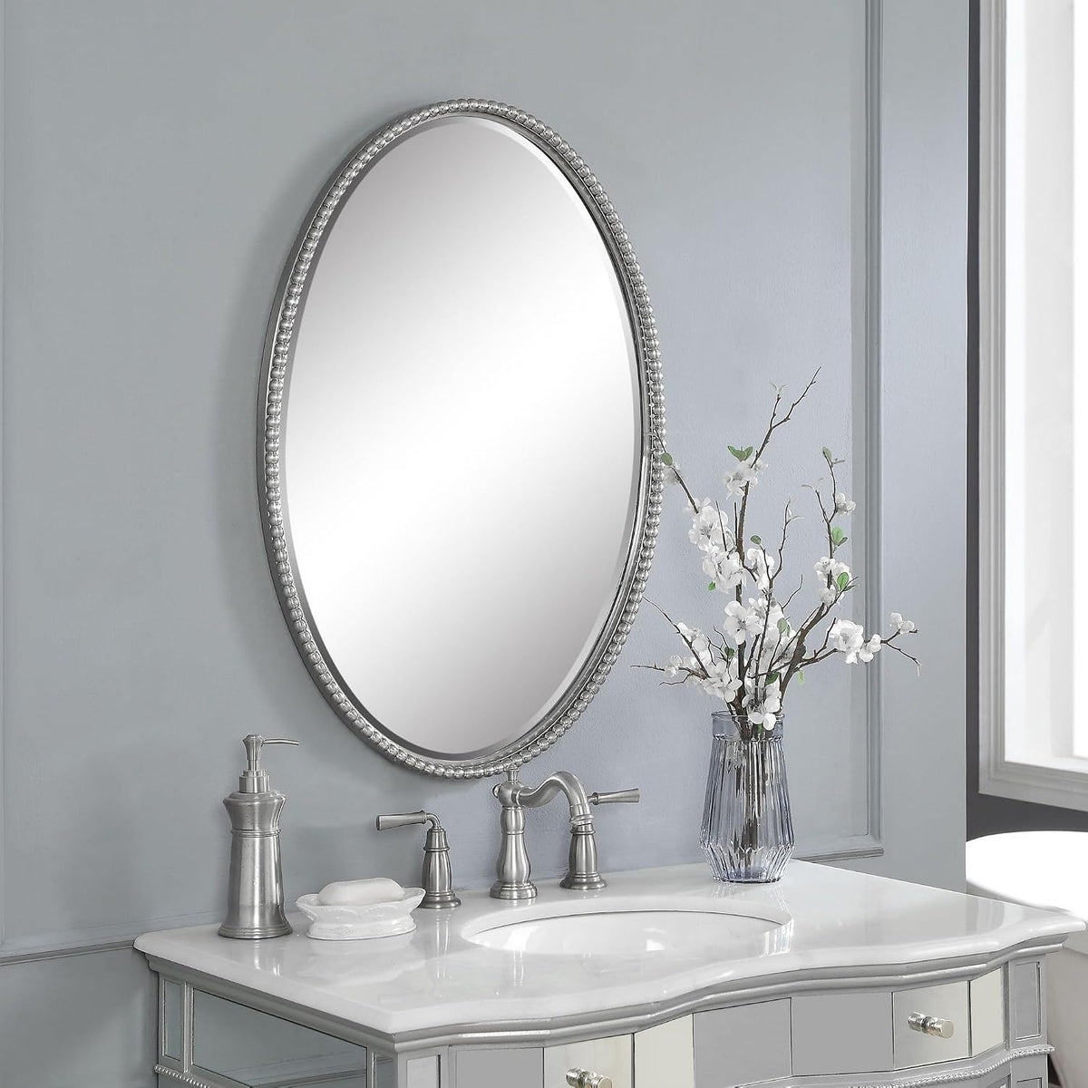 Brushed nickel oval mirror viewed at an angle above a vanity
