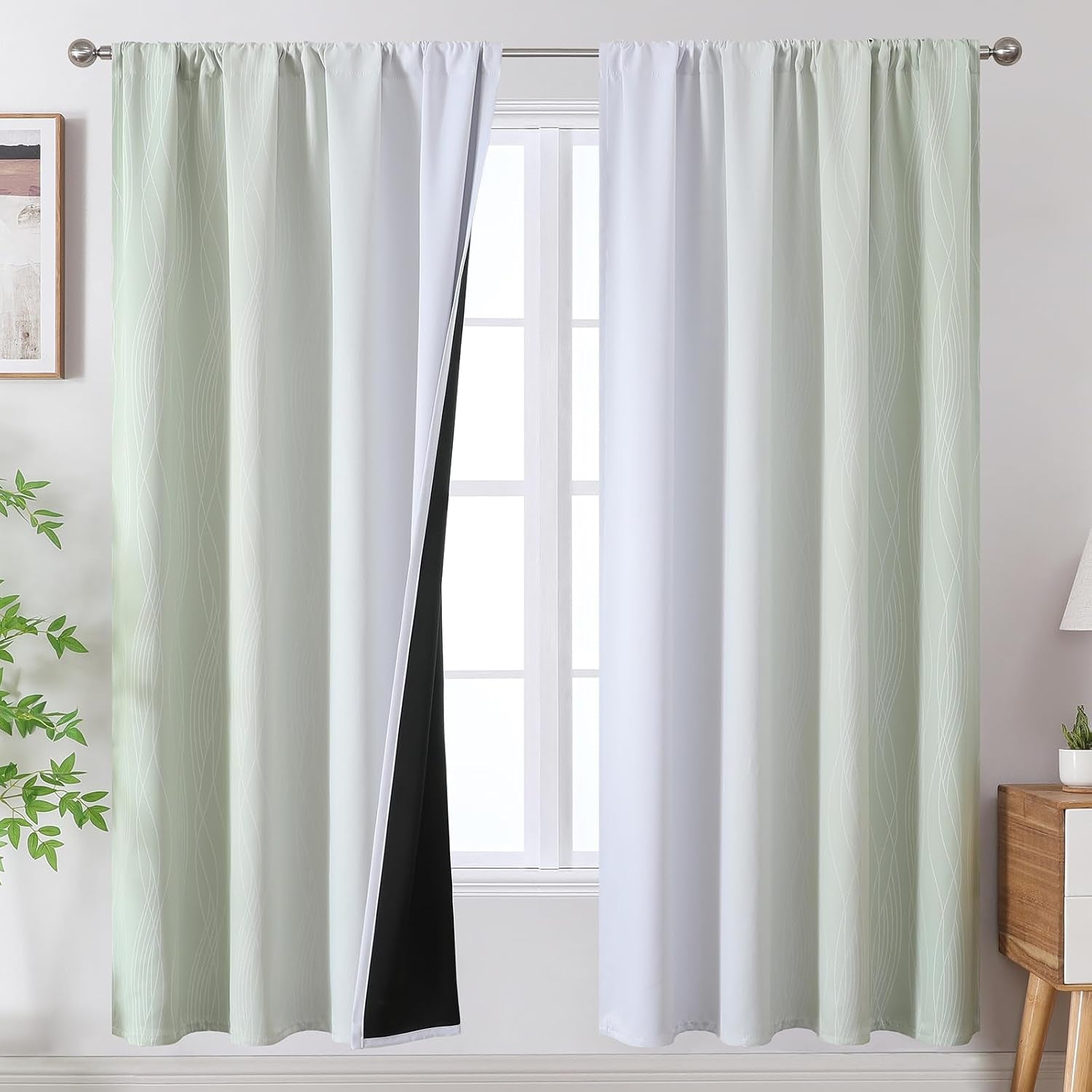 Light green and white ombre curtains shown full length with slight gathers, one panel folded back to show black blackout