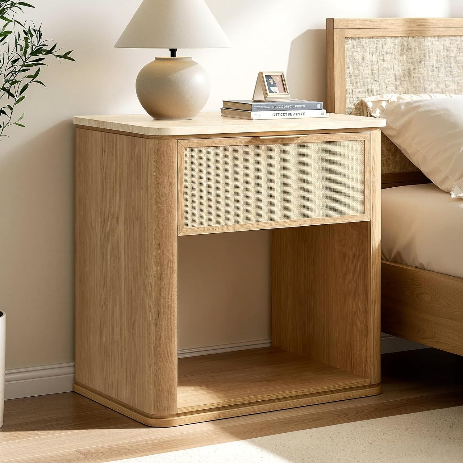 Light oak bedside table with one woven-front drawer and open shelf below, lamp on top.