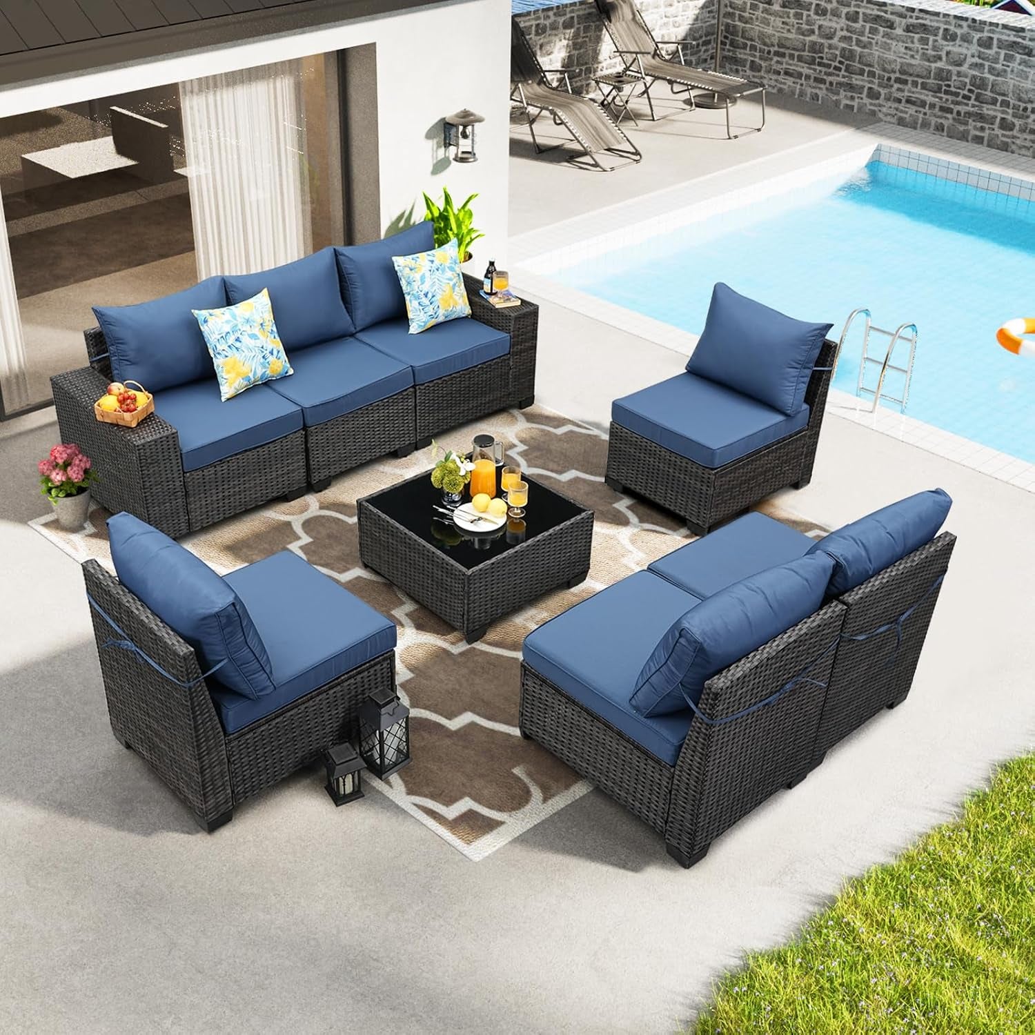 Top-down view of the same rattan sectional displayed with blue cushions arranged around a square glass coffee table by a