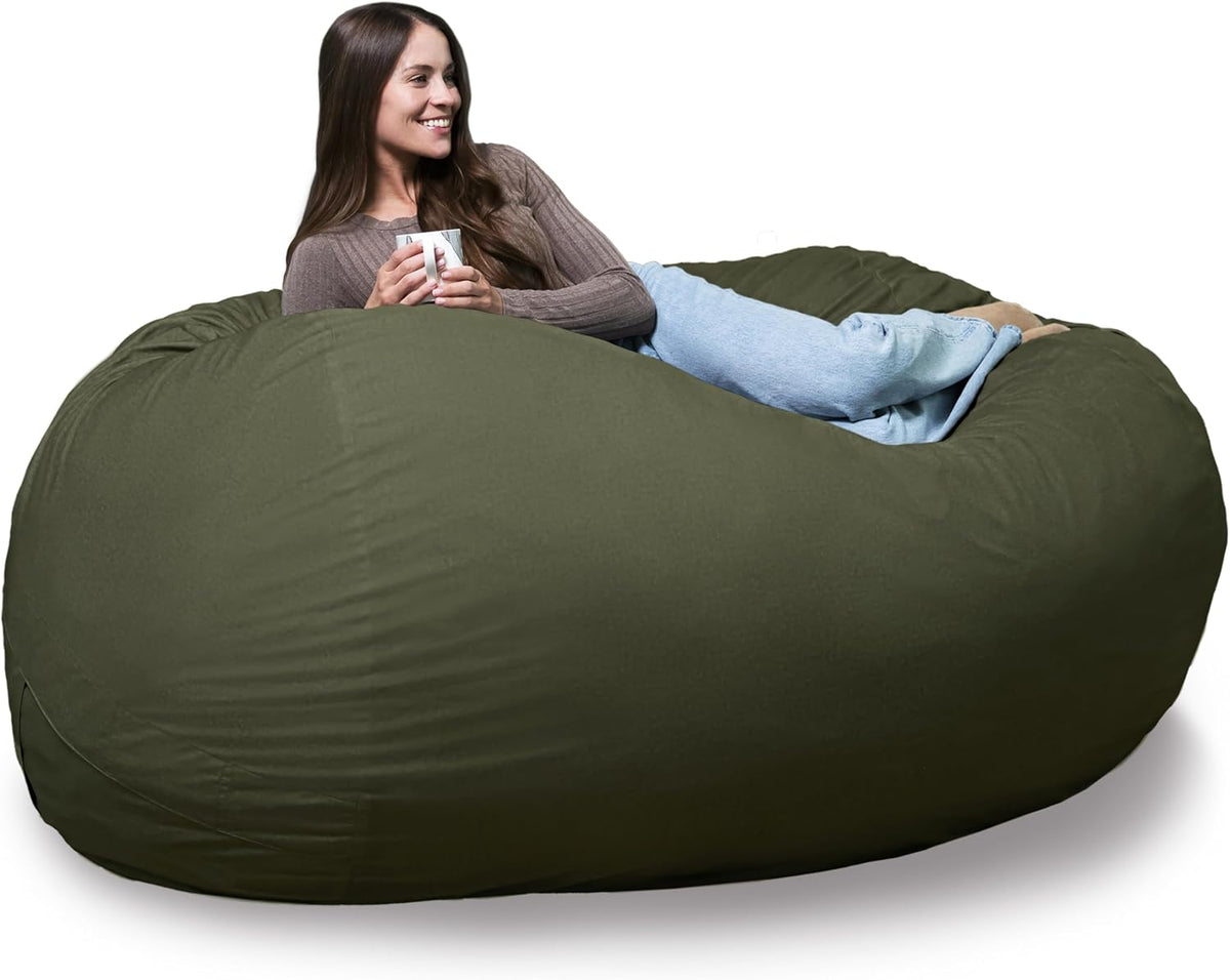 Woman lounging sideways on an olive-green oversized bean bag holding a mug.