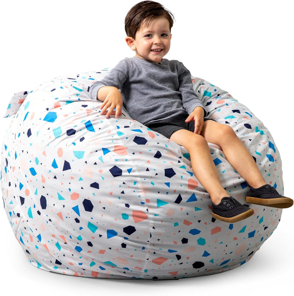 Child reclining on a large white bean bag with blue and pink terrazzo-like shapes