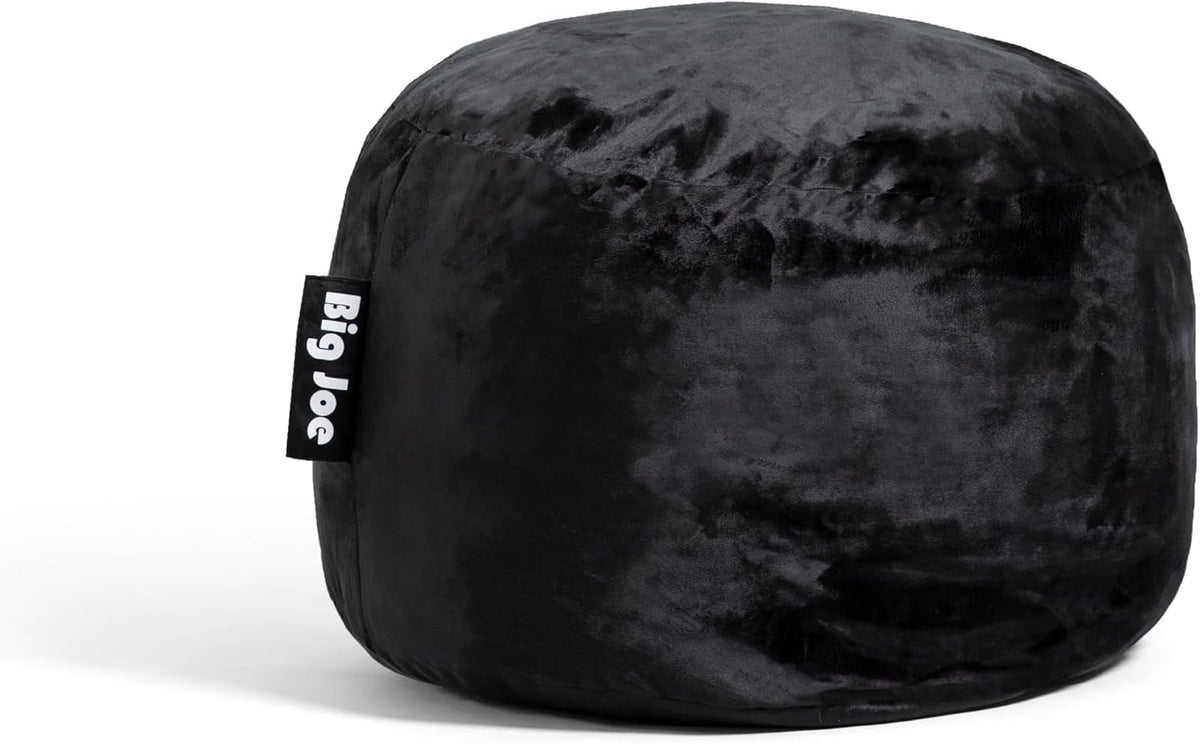Close-up three-quarter view of a small black velvety pouf with a fabric side tag.
