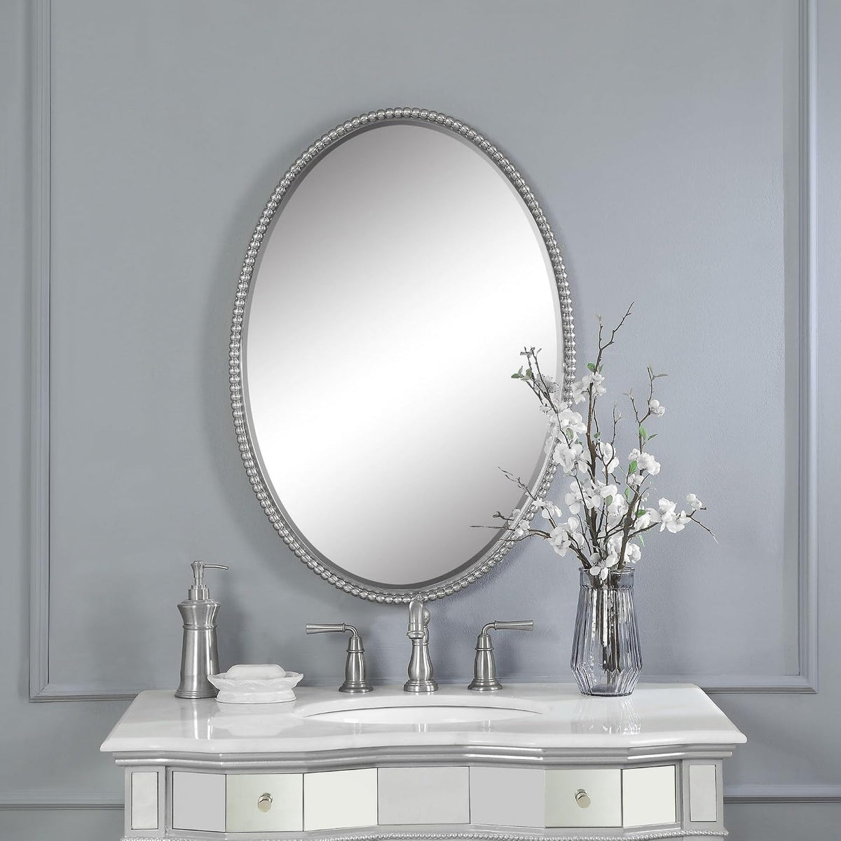 Oval beaded-frame mirror mounted above a bathroom vanity