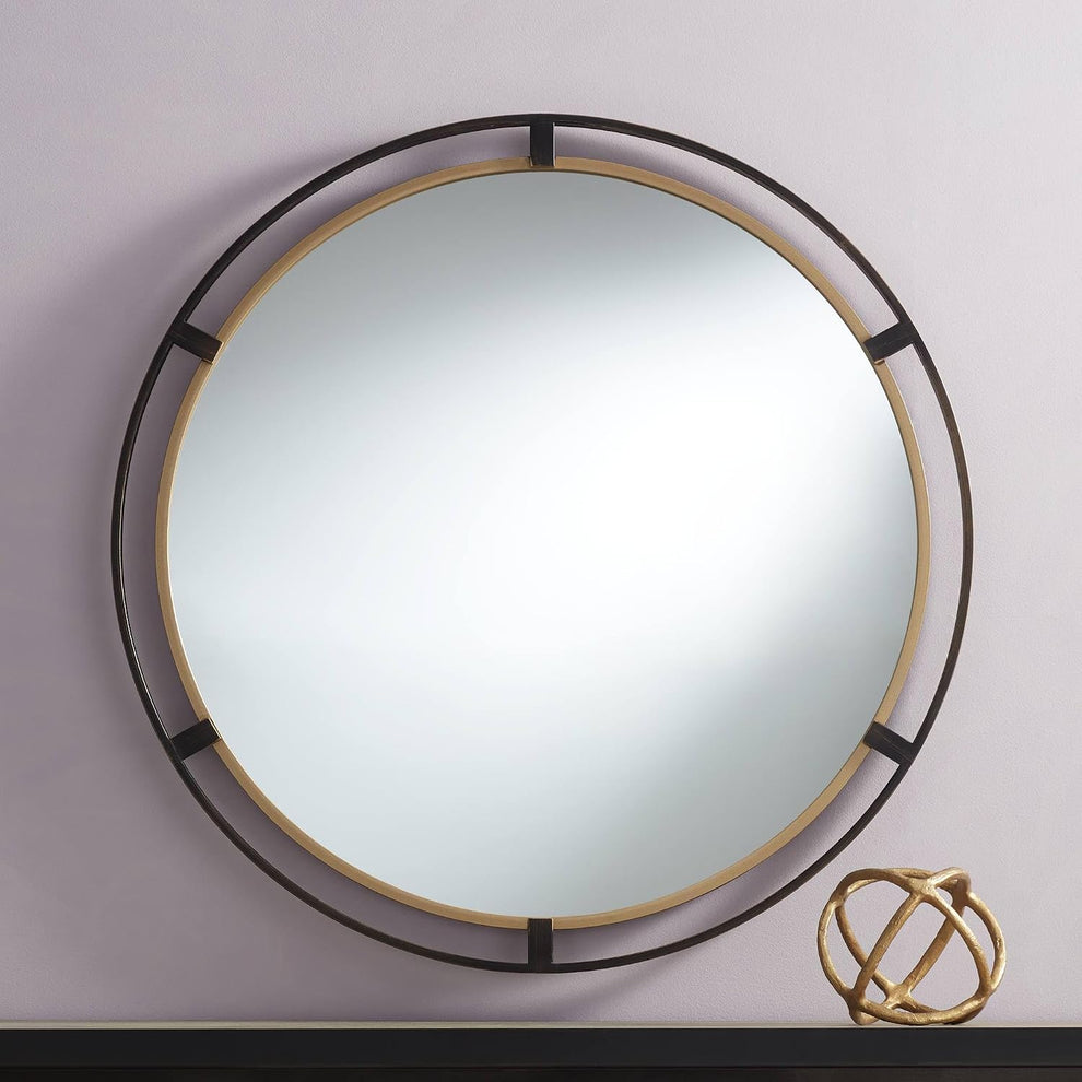 Round metal wall mirror with inner antiqued gold ring and outer rustic bronze ring, angled front view on a pale wall