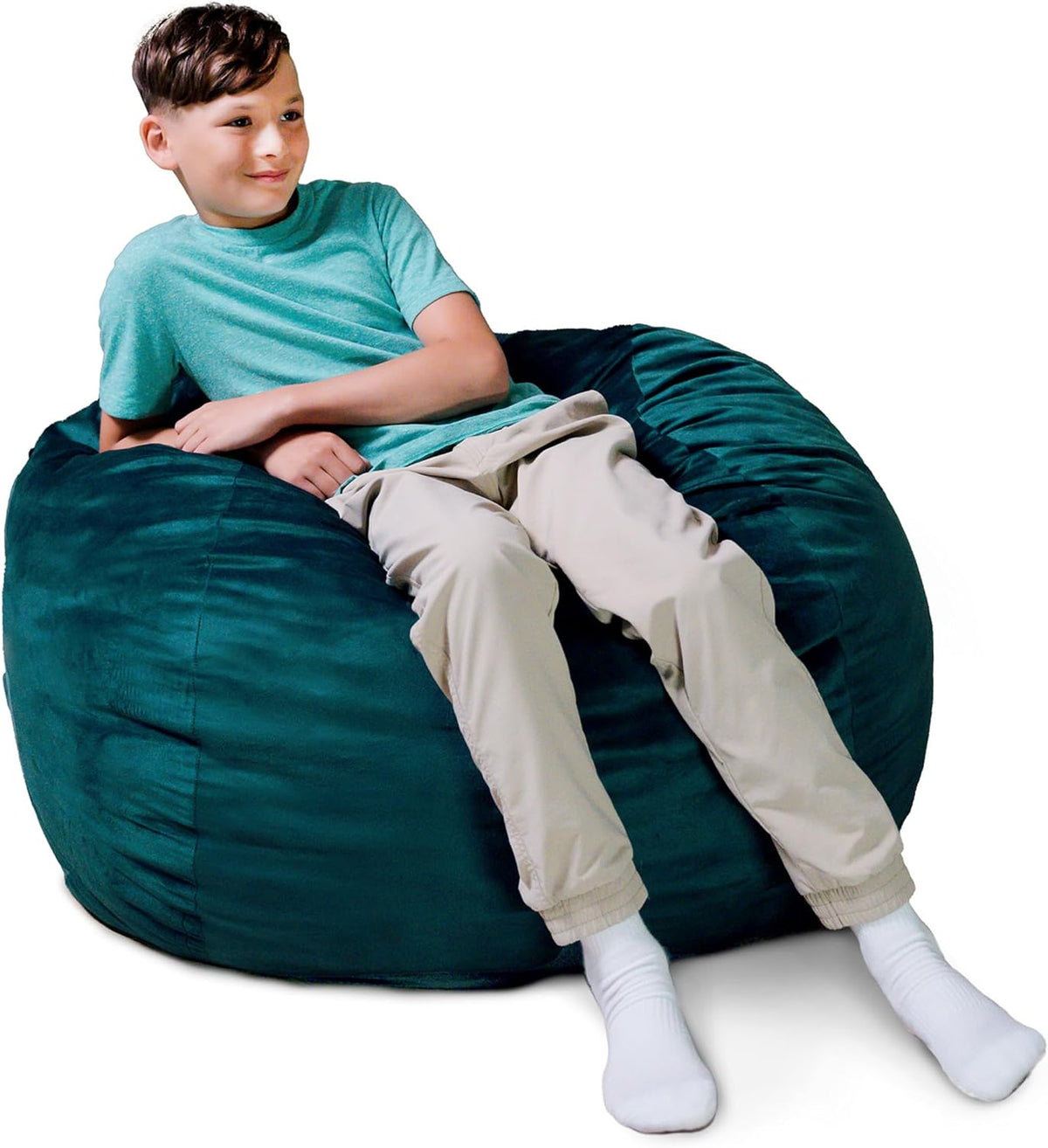 Teen boy leaning back on a deep teal oversized bean bag with his legs extended toward the viewer.