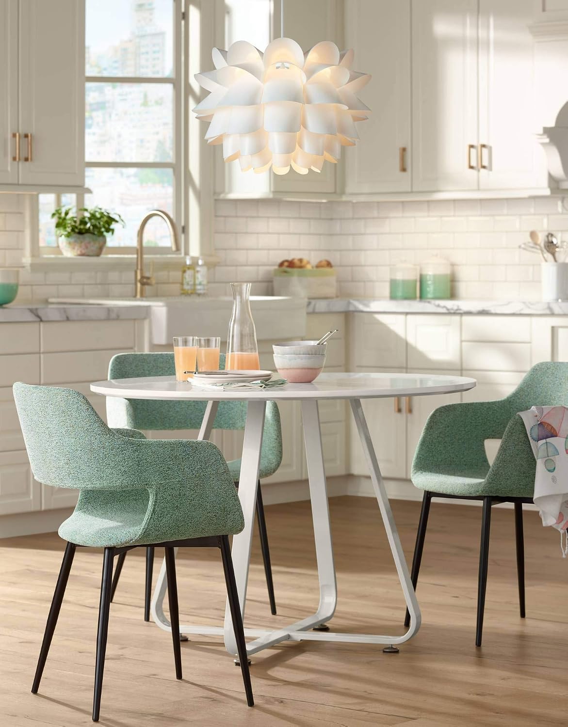 Pendant centered over a round dining table set with glasses, surrounded by mint-green upholstered chairs.