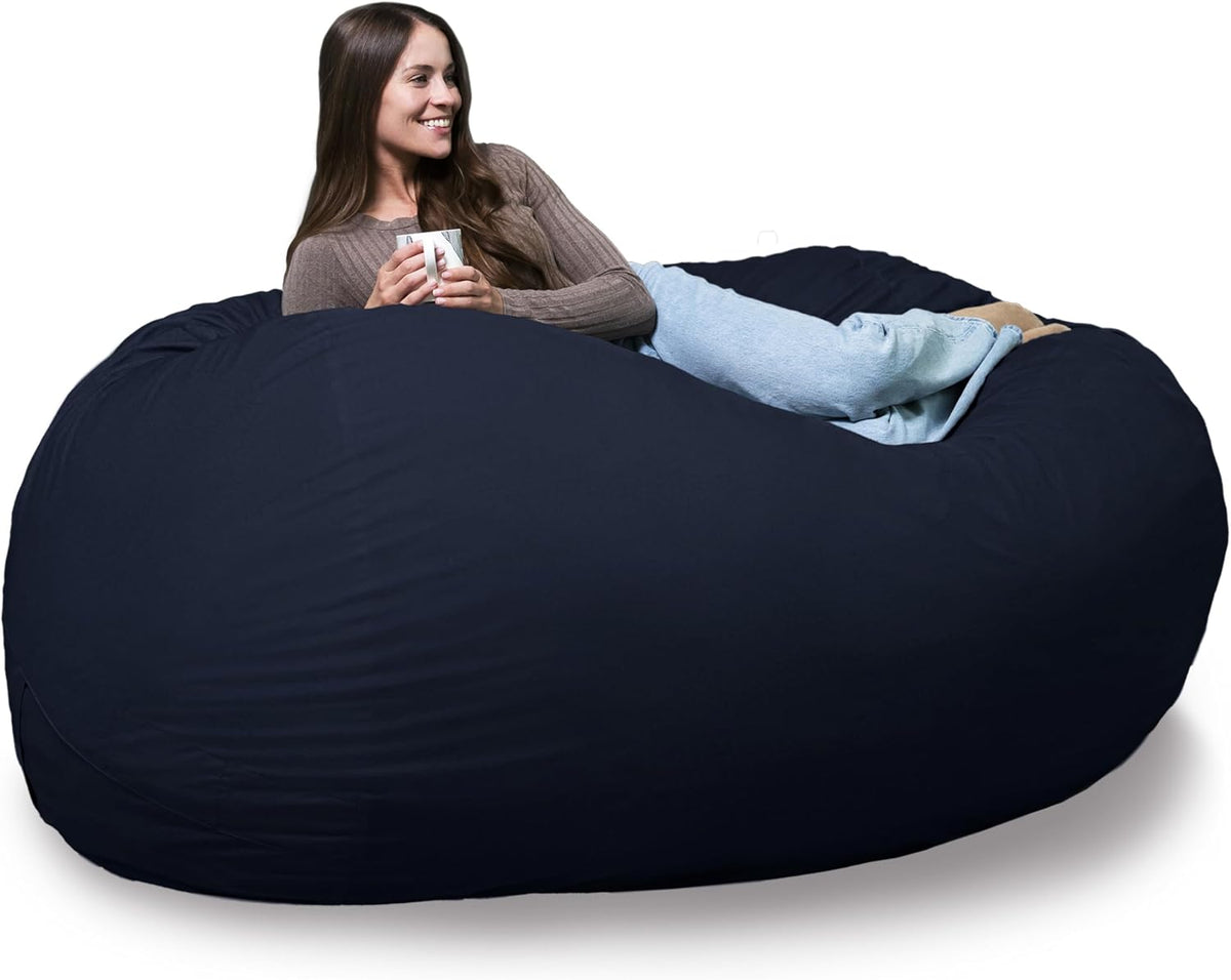 Side-angle shot of a woman reclining with a mug on a deep navy oversized lounger.