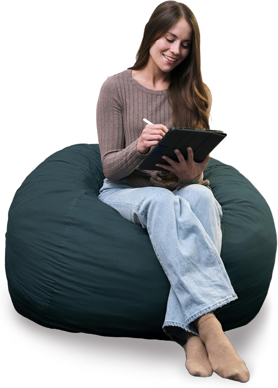 Smiling woman writing on a tablet while seated on a dark teal smooth lounger with legs crossed.