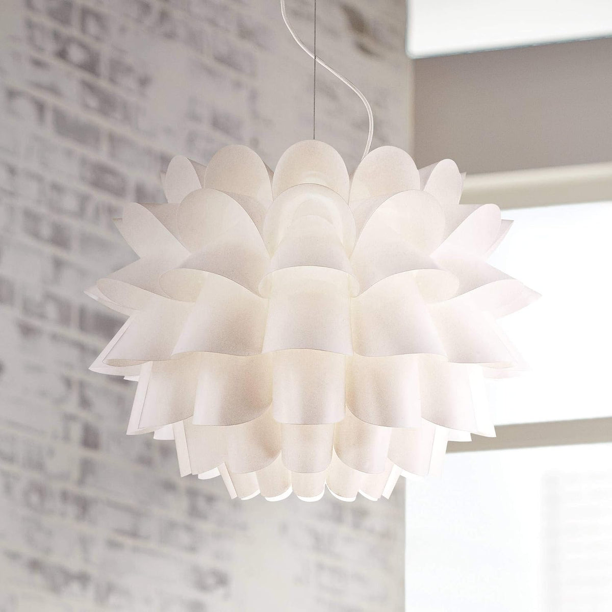 Overhead close-up of scalloped translucent petals and layered edges against a blurred brick wall.