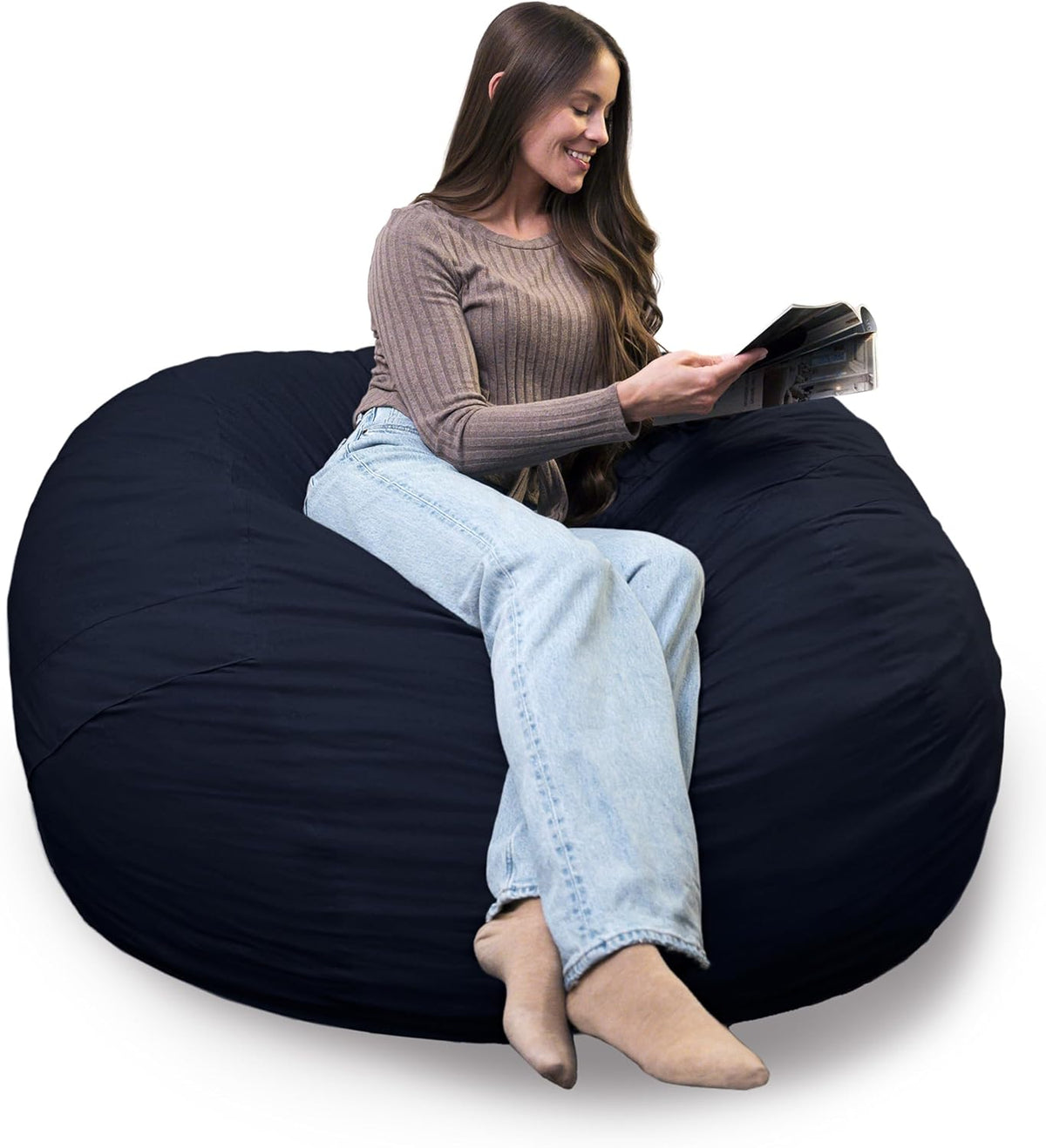 Woman reclining cross-legged on a navy oversized lounger reading a magazine.