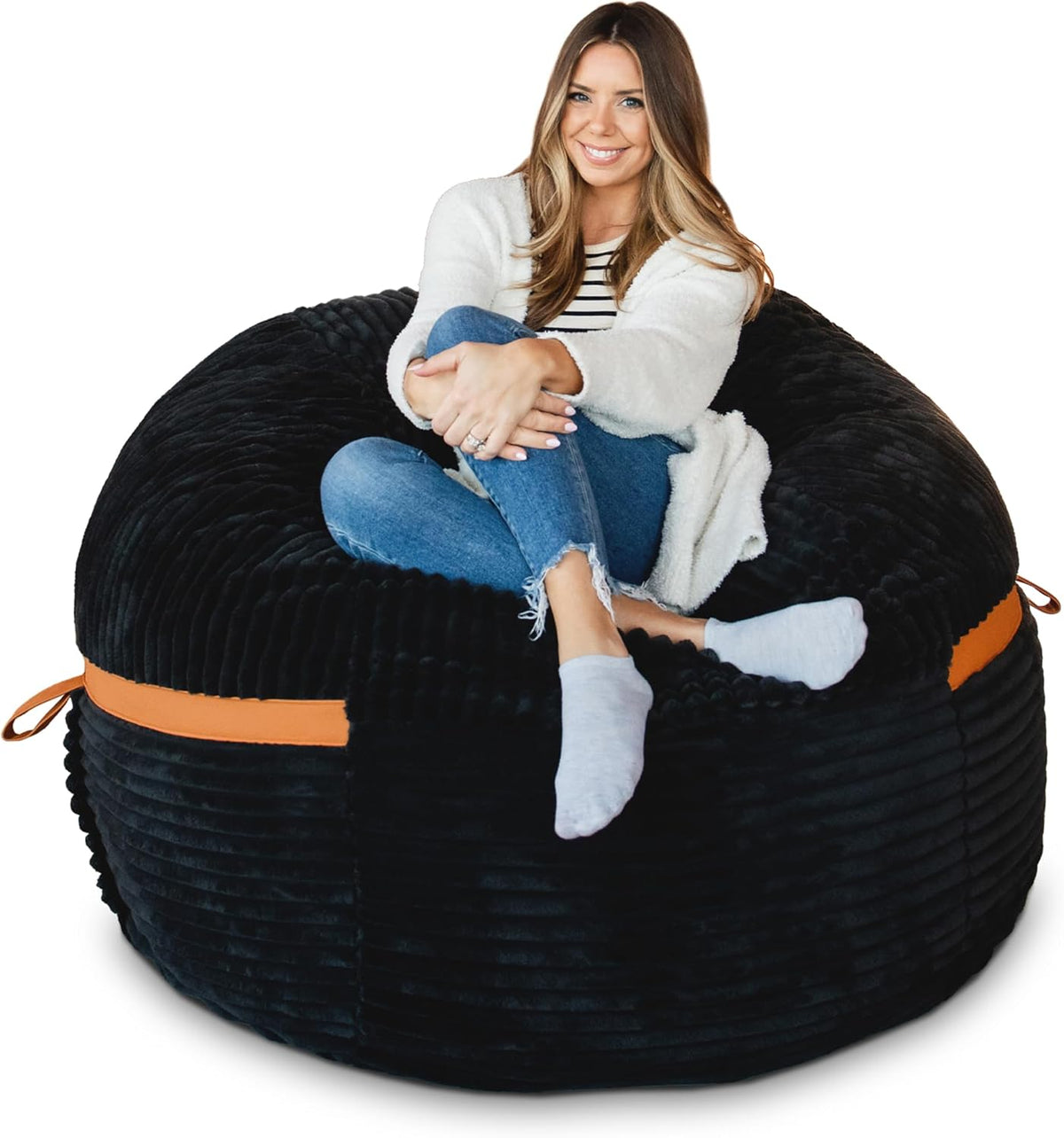 Woman seated cross-legged in a black ribbed lounger with tan carry strap visible.