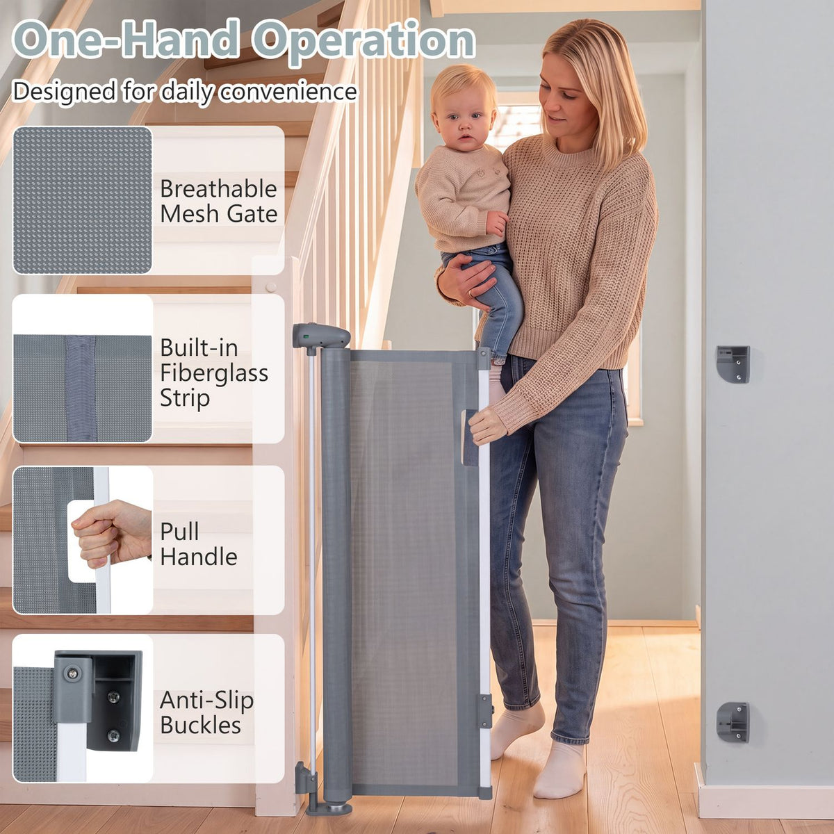 A woman operates a gray mesh gate beside a staircase while holding a baby.