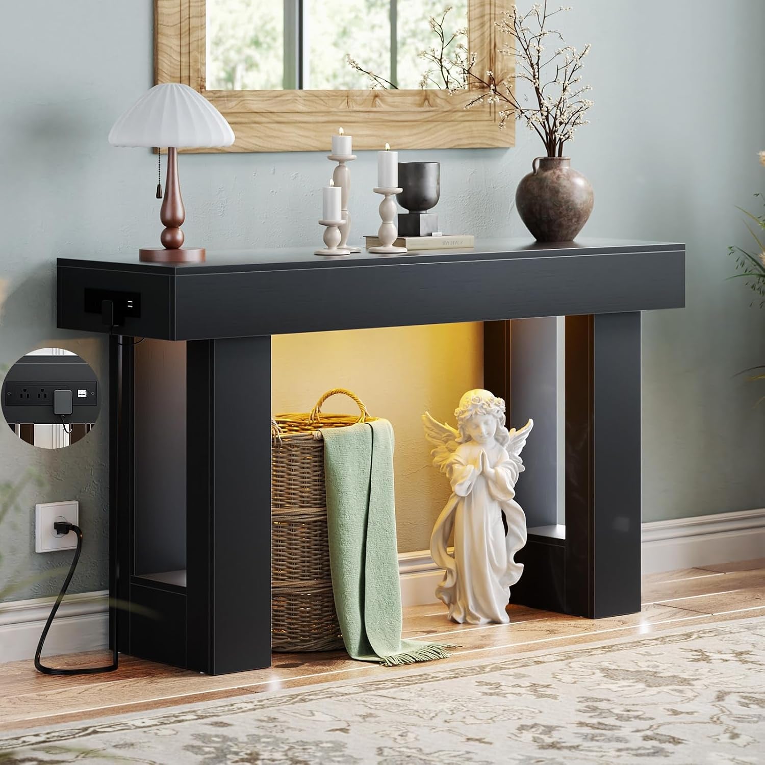 Three-quarter front view of a black console table with mirror above, tabletop decor and illuminated recess below