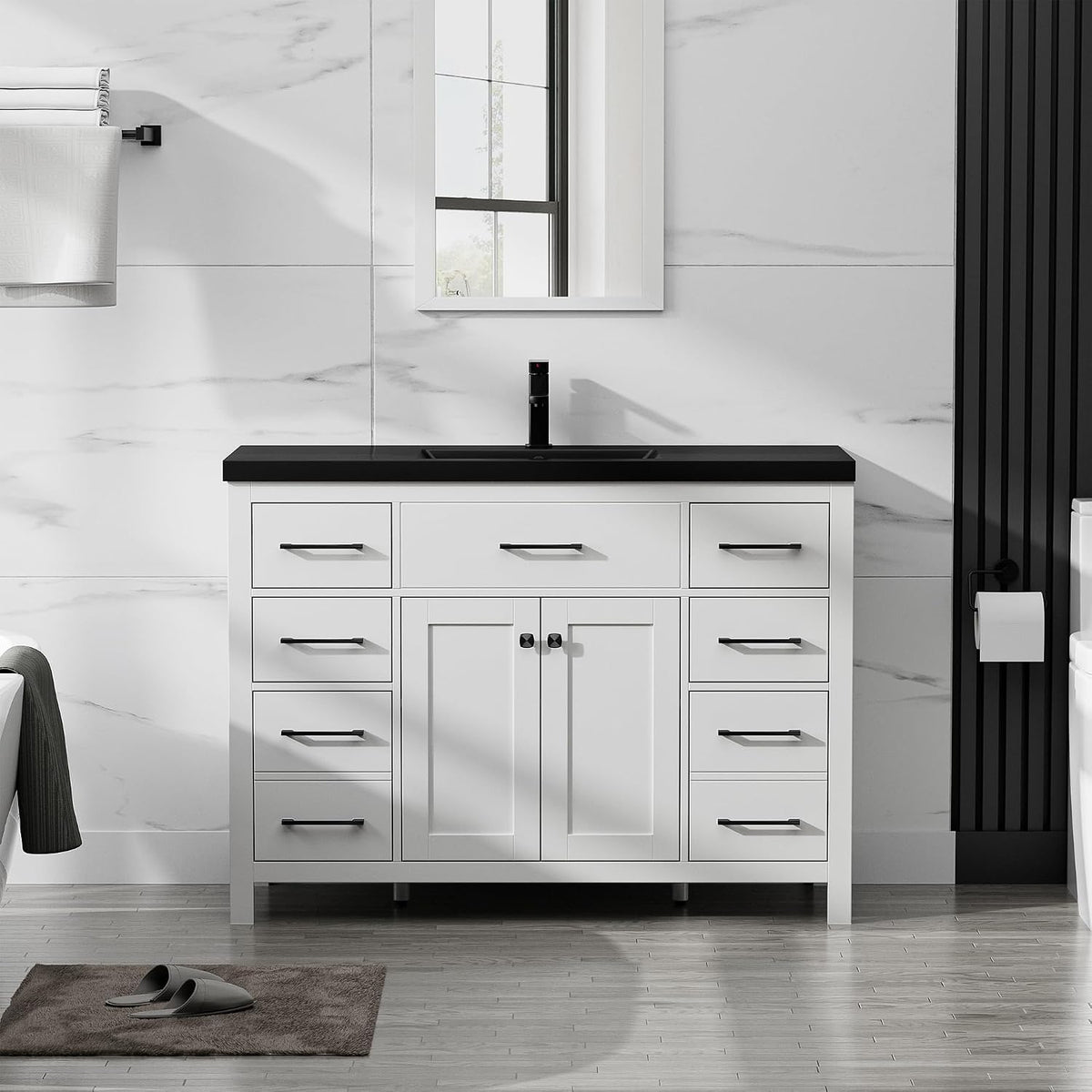 White single-sink vanity with black countertop and centered faucet, framed mirror and towel on left.
