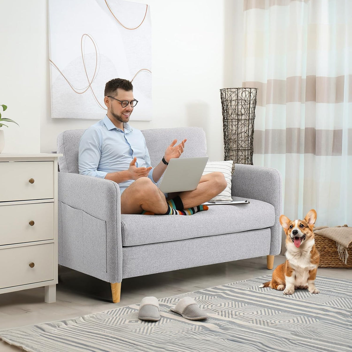Light-gray small loveseat in a living room with a man on laptop and a corgi on the rug