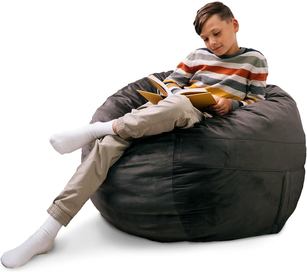 Boy reading while reclining on a large dark-gray oversized bean bag chair