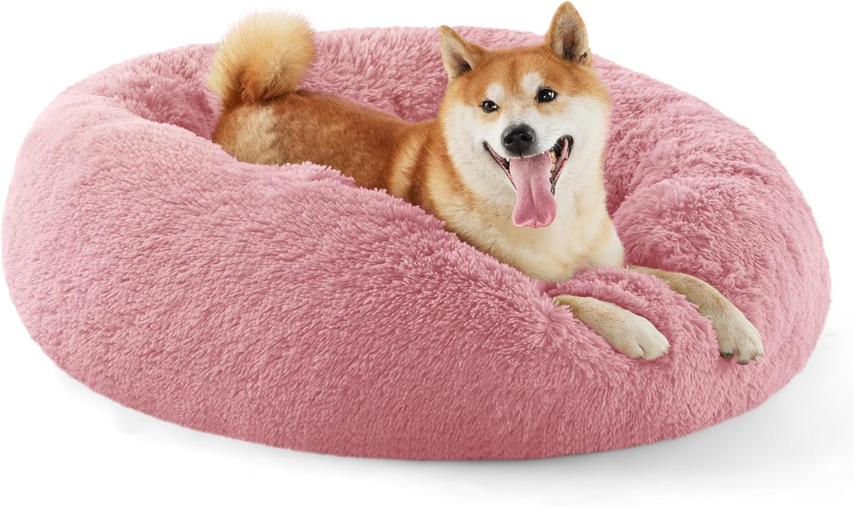 Three-quarter side view of a pink fluffy round bed with a panting Shiba Inu lounging inside.
