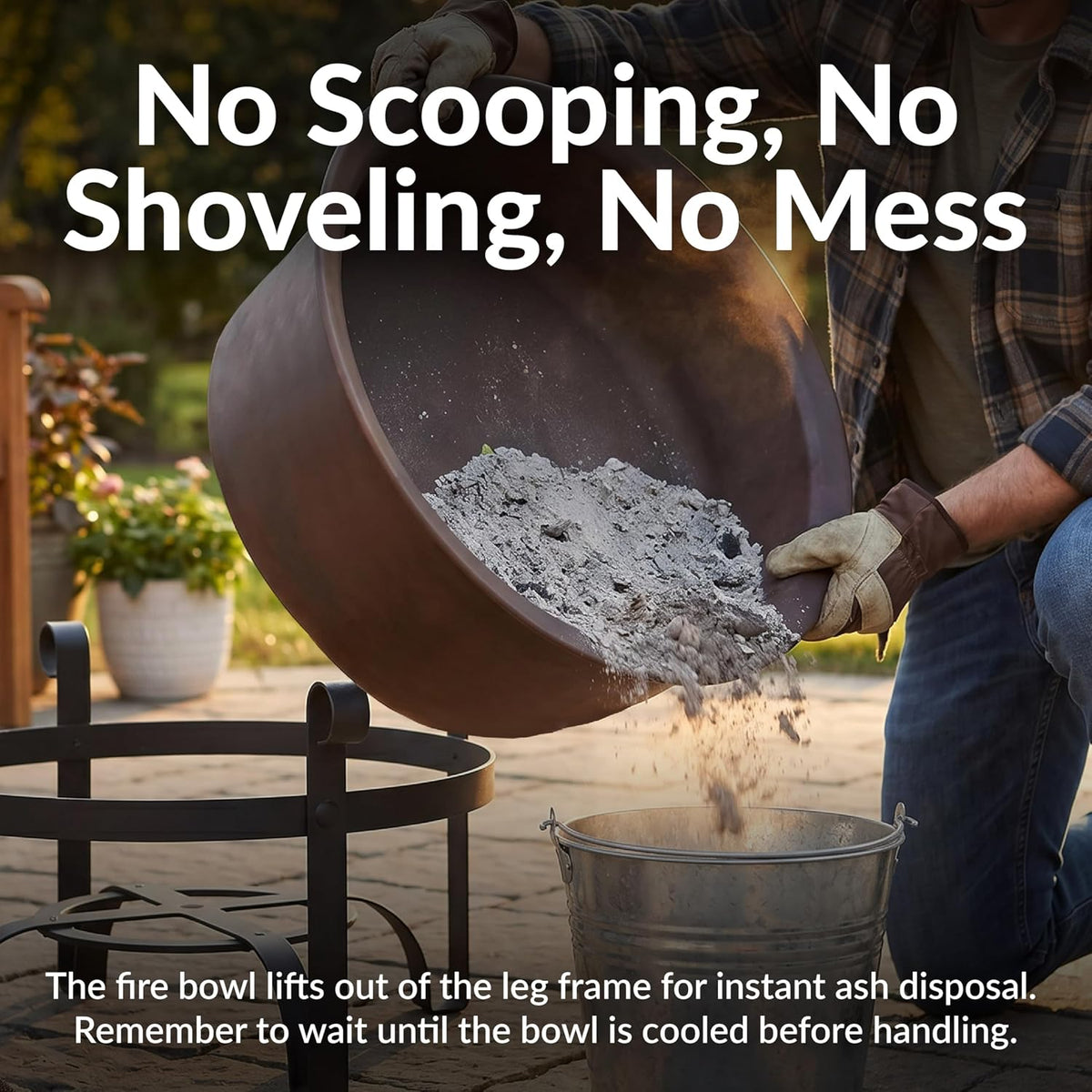 Removable dark bronze fire bowl being lifted out to pour ash into a bucket in an outdoor setting