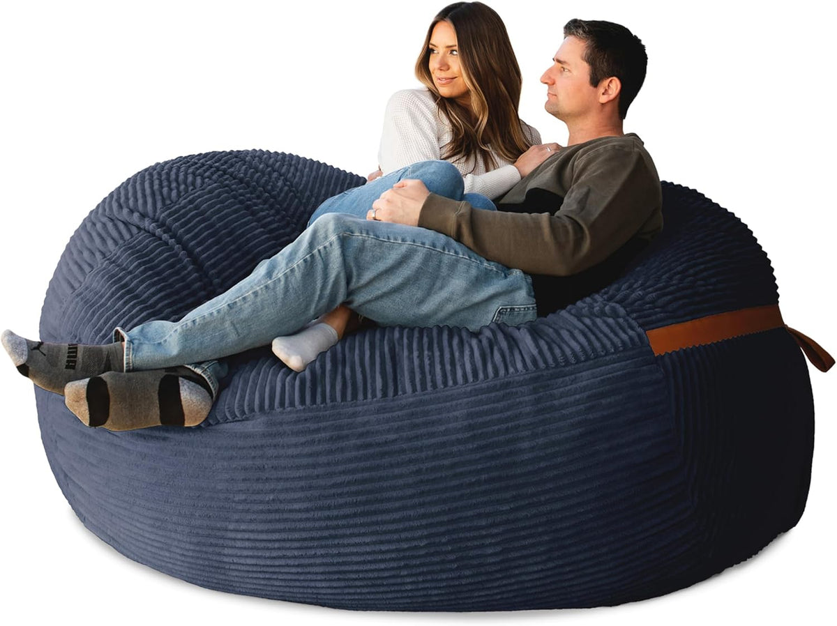 Couple reclining together on a deep navy oversized lounger, angled side view with tan strap detail