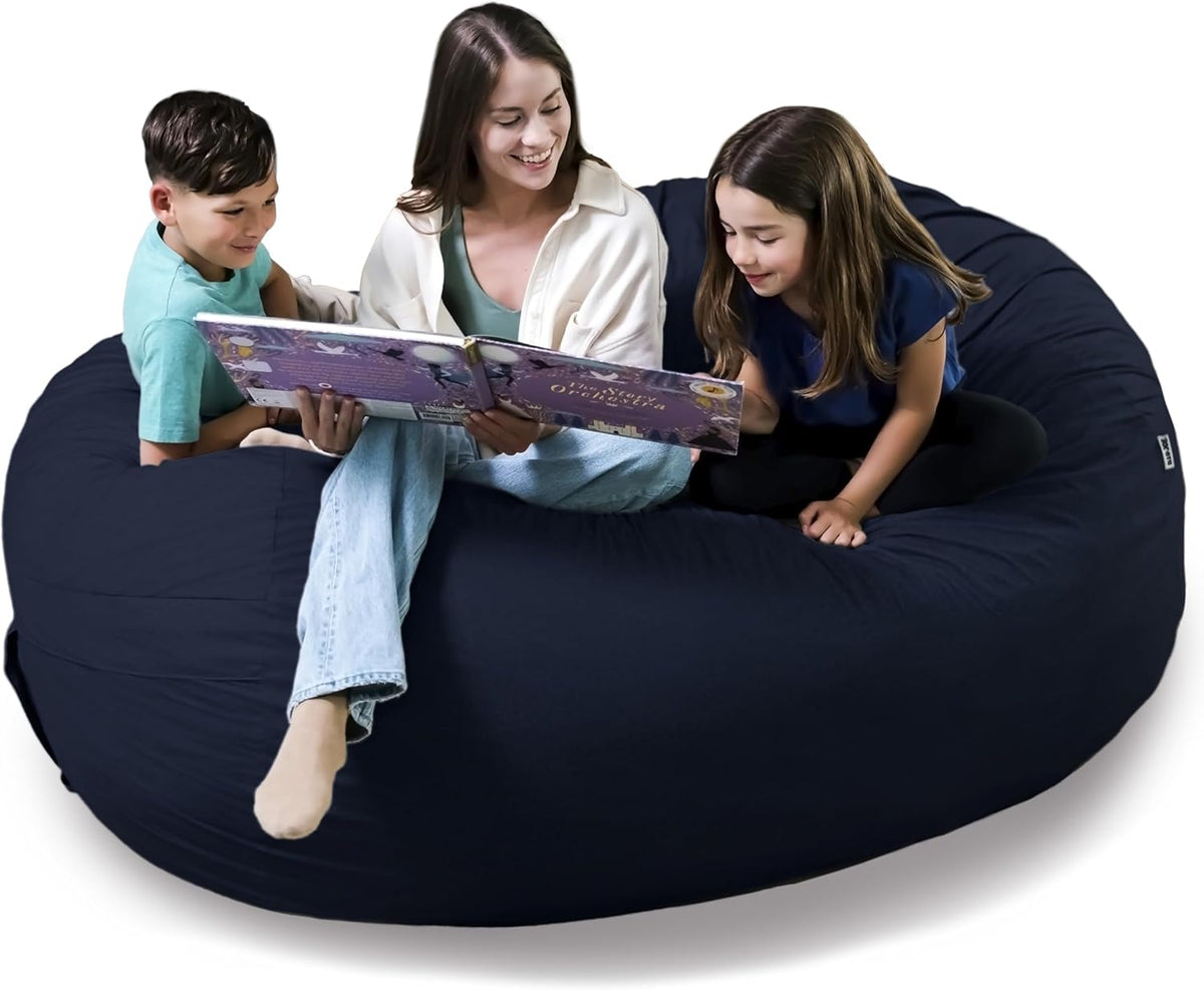 Adult reading a book with two children seated on a dark navy giant bean bag couch.