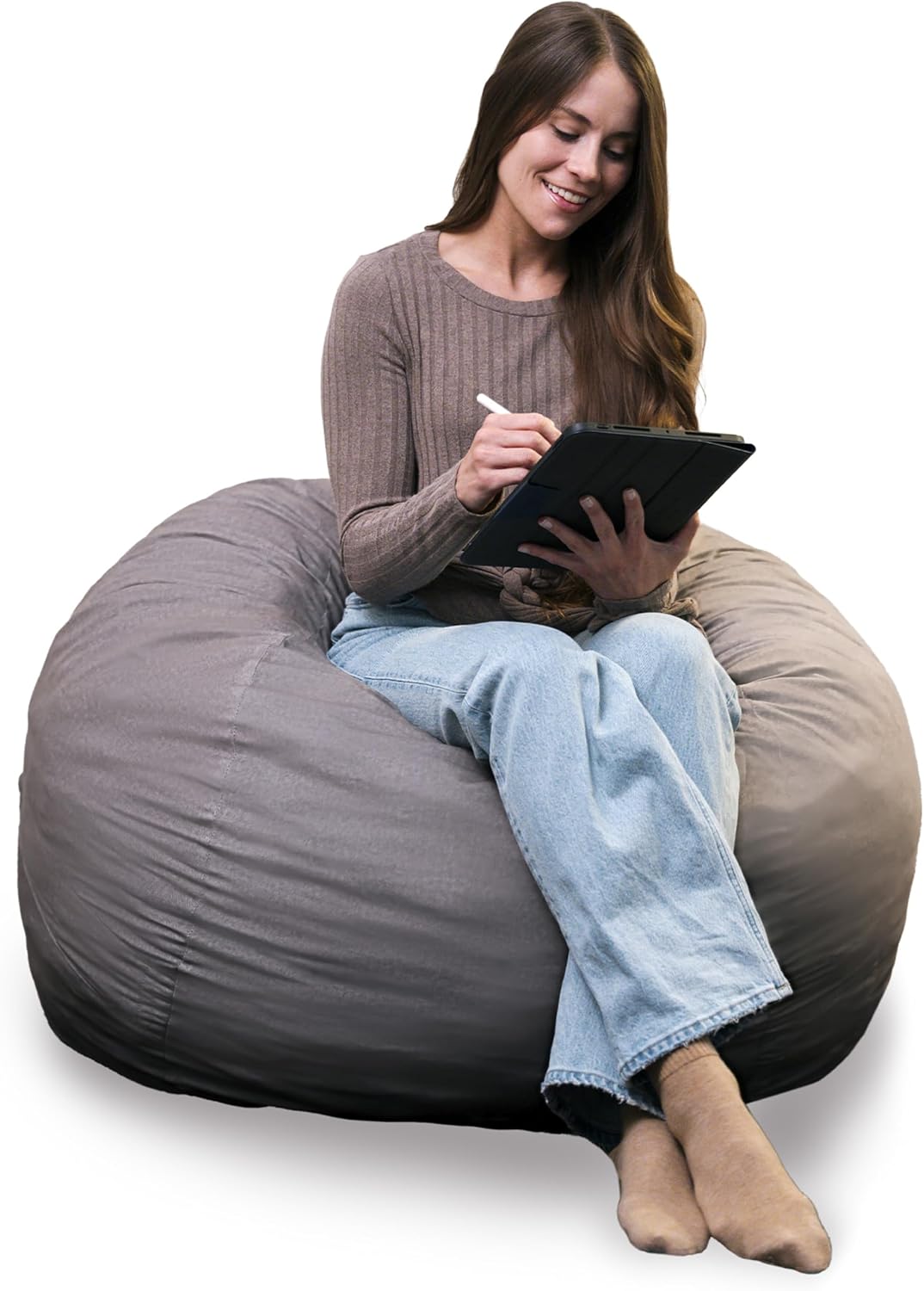 Cropped view of a woman sitting upright and writing on a tablet on a warm gray lounger.