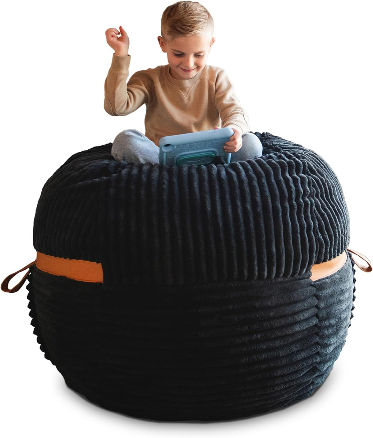 Child sitting cross-legged on a black ribbed oversized lounger with tan leather strap detail