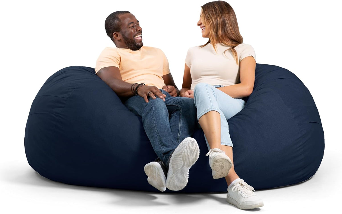 Man and woman sitting together on a large navy bean bag, smiling and facing each other