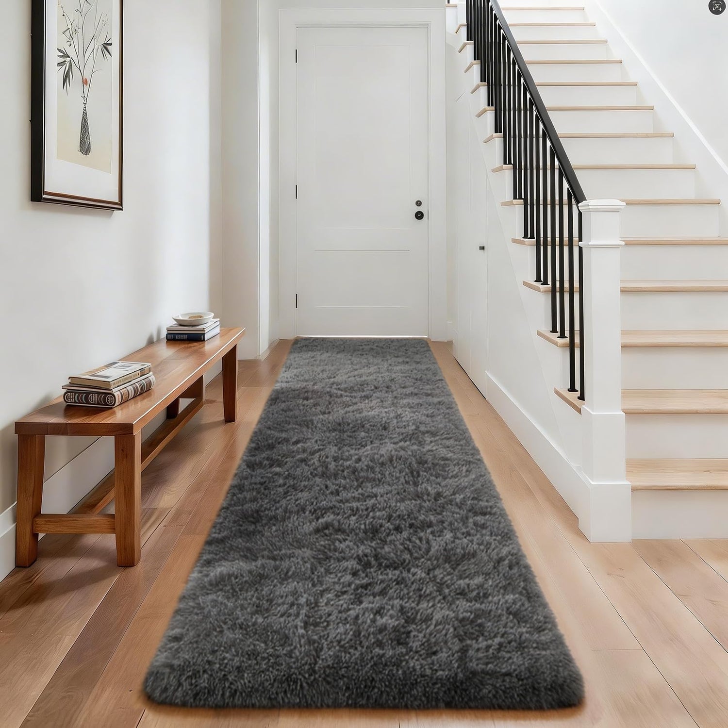 Long dark gray shag runner placed down a bright hallway beside a wooden bench and staircase.