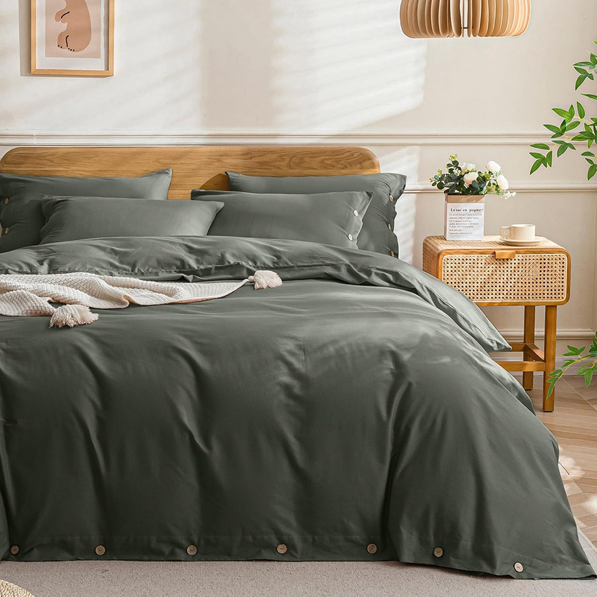 Deep olive-gray duvet on a styled bed with a cream knit throw draped across the foot and sunlit wall shadows.