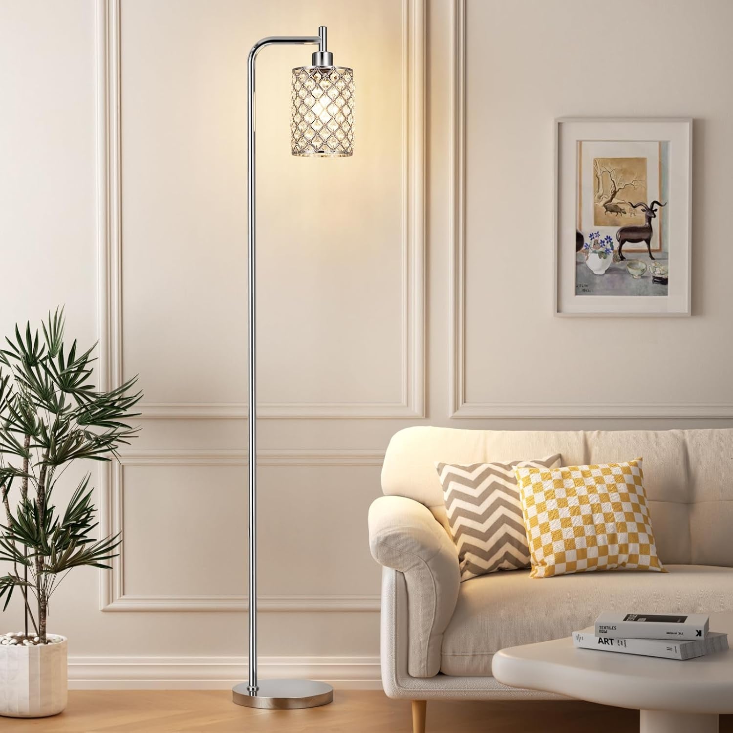 Tall chrome-finish floor lamp with clear glass shade beside a beige sofa in a living room.