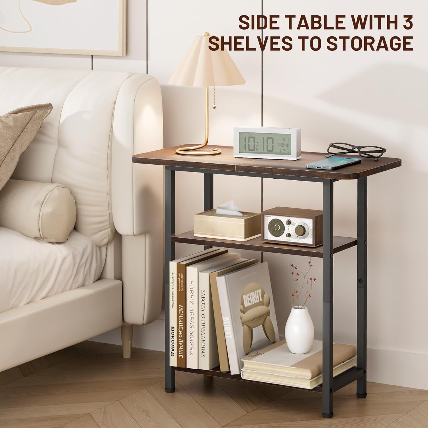 Narrow end table beside bed shown with lamp and books on three open shelves in bedroom setting