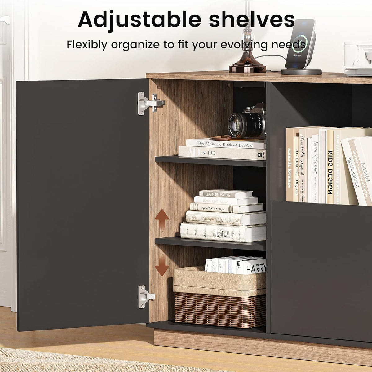 Open cabinet door revealing wood-tone interior, adjustable black shelves holding books, a camera and a woven basket.
