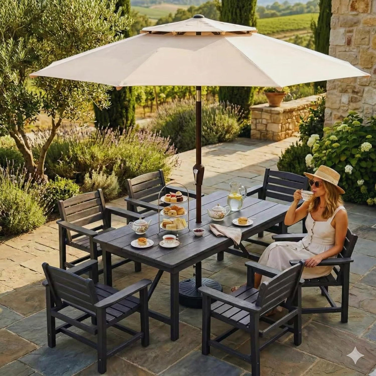 Patio dining set under a beige umbrella with a woman in a sunhat sitting and sipping tea.