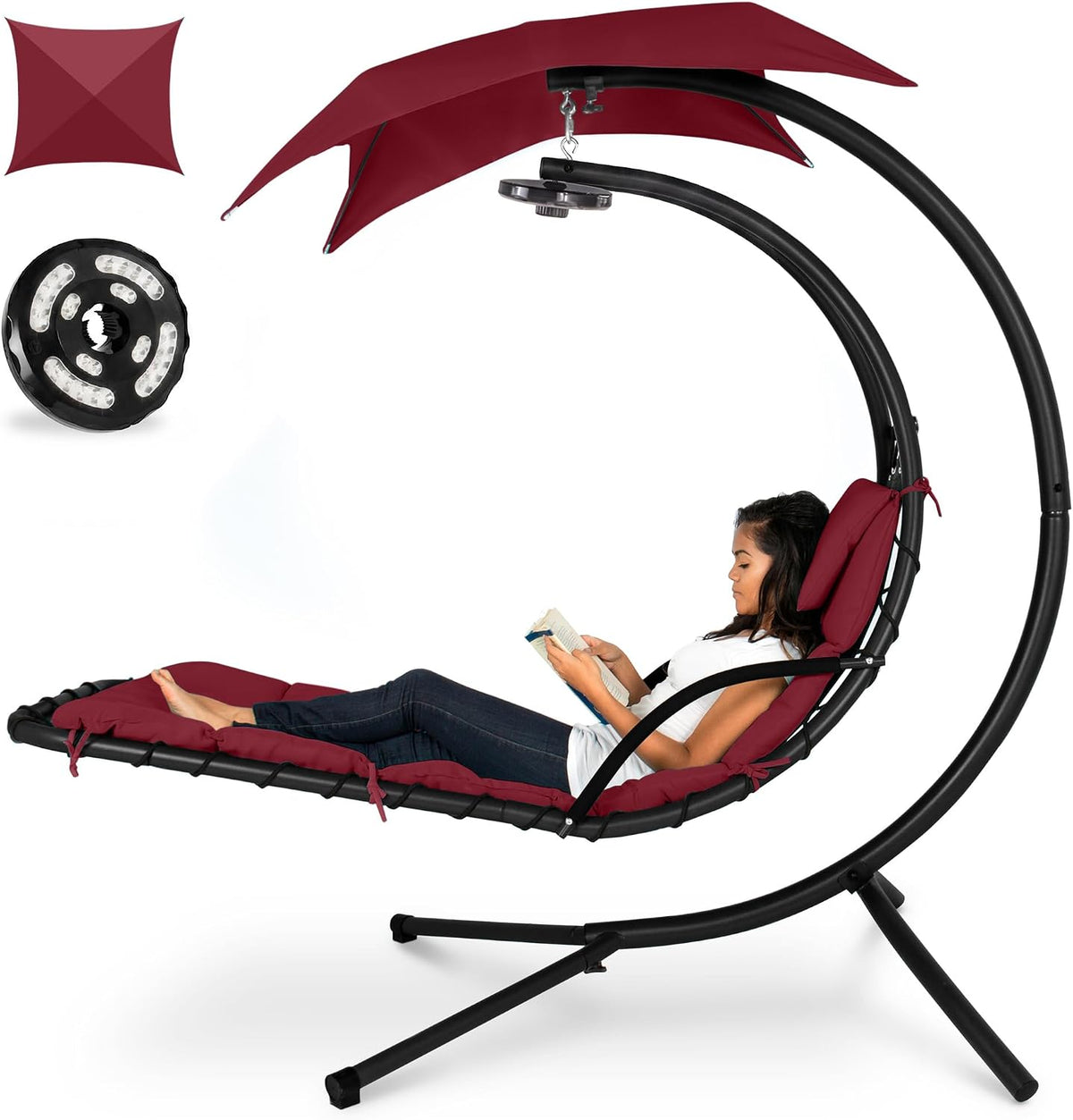 Curved hanging chaise in burgundy red with matching cushions and canopy, woman relaxing with a book.