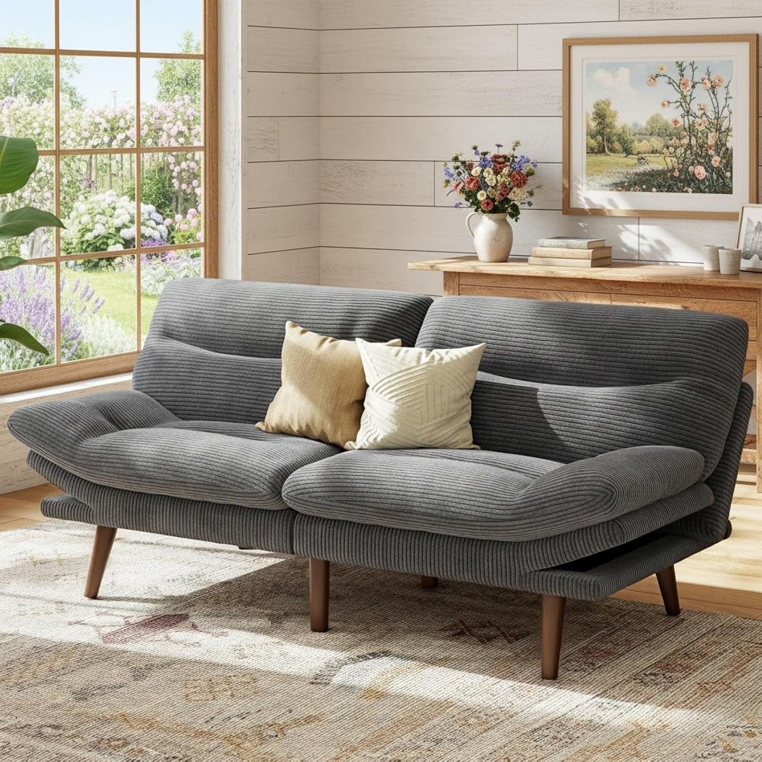 Gray corduroy futon with two accent pillows placed near a window and console table