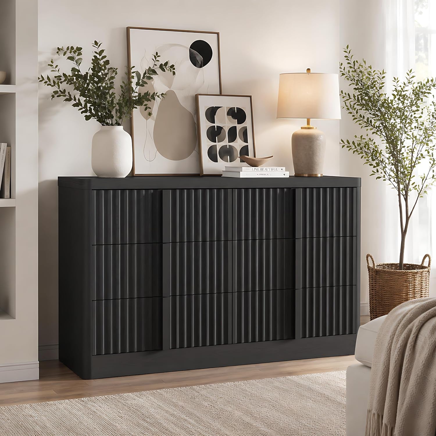 Black fluted dresser styled in a living room with lamp, framed art, and potted plants