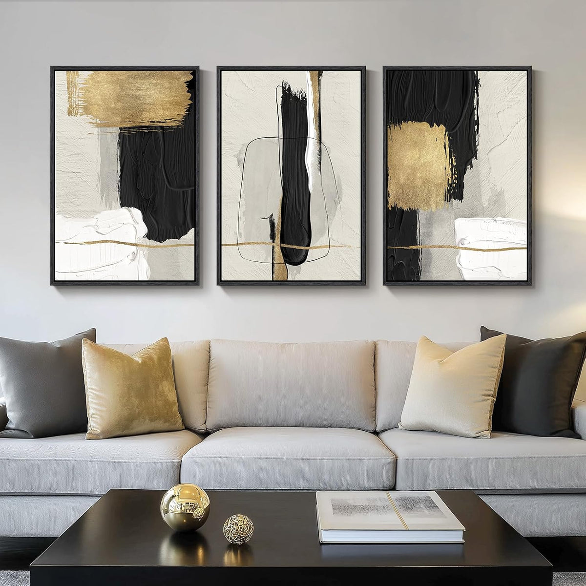 Three-panel abstract set with black brushwork and gold highlights above a light sofa, bedside lamp visible at right.