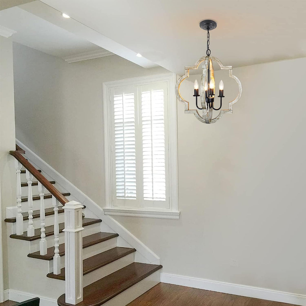 Chandelier installed above a stair landing in a bright foyer with white trim and wooden stair treads