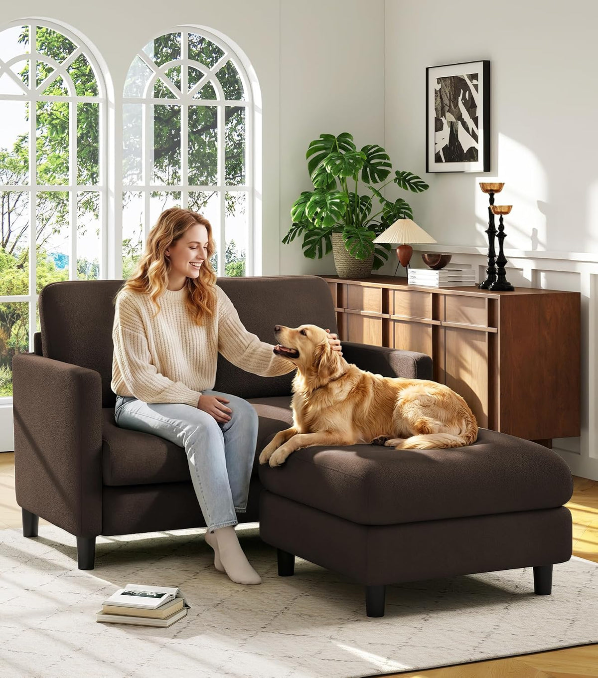 Woman petting a golden retriever lying on a brown loveseat with matching ottoman chaise.