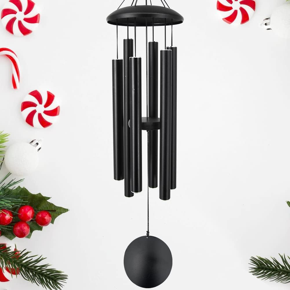 Front view of a black metal wind chime with six tubular chimes and round sail, festive greenery at edges