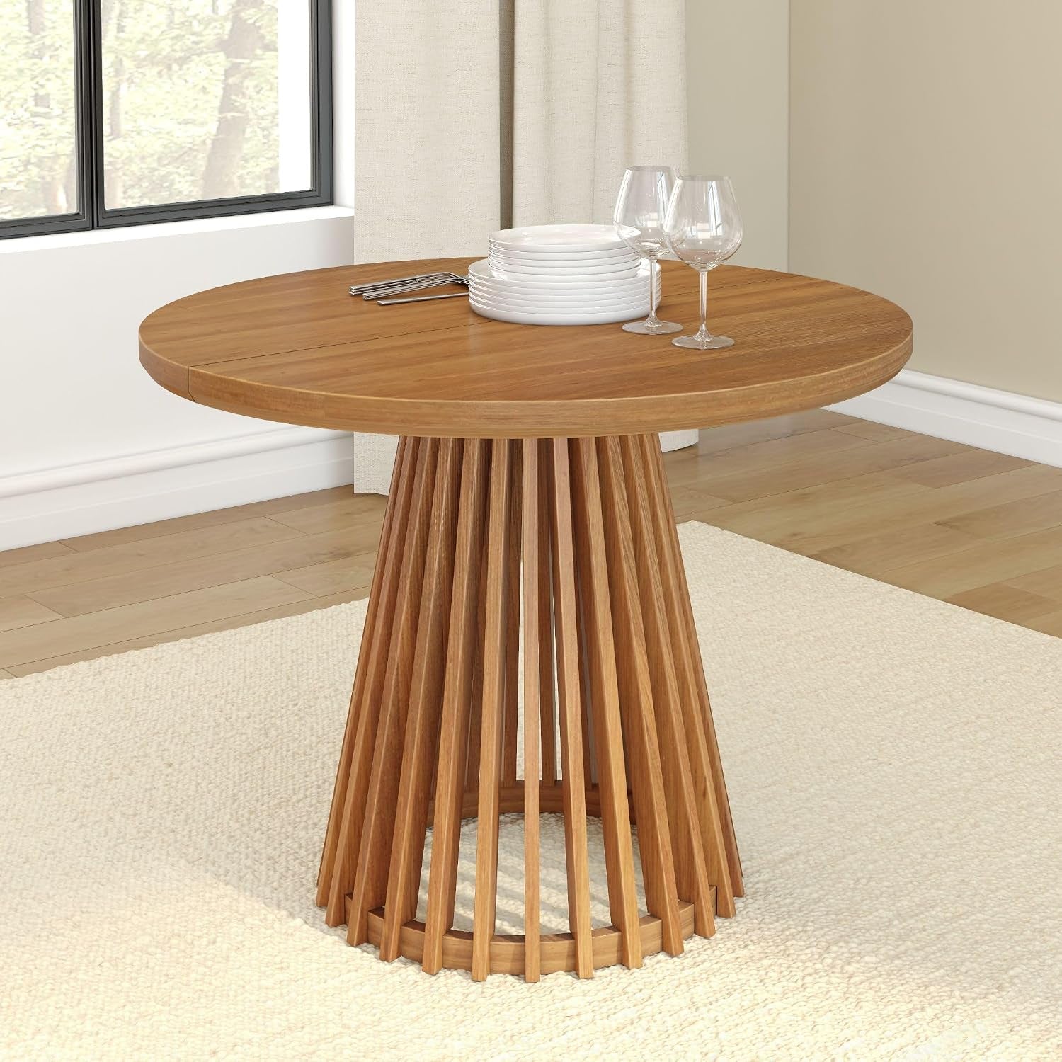 Round medium-tone wood dining table with tapered slatted pedestal and stacked plates on top