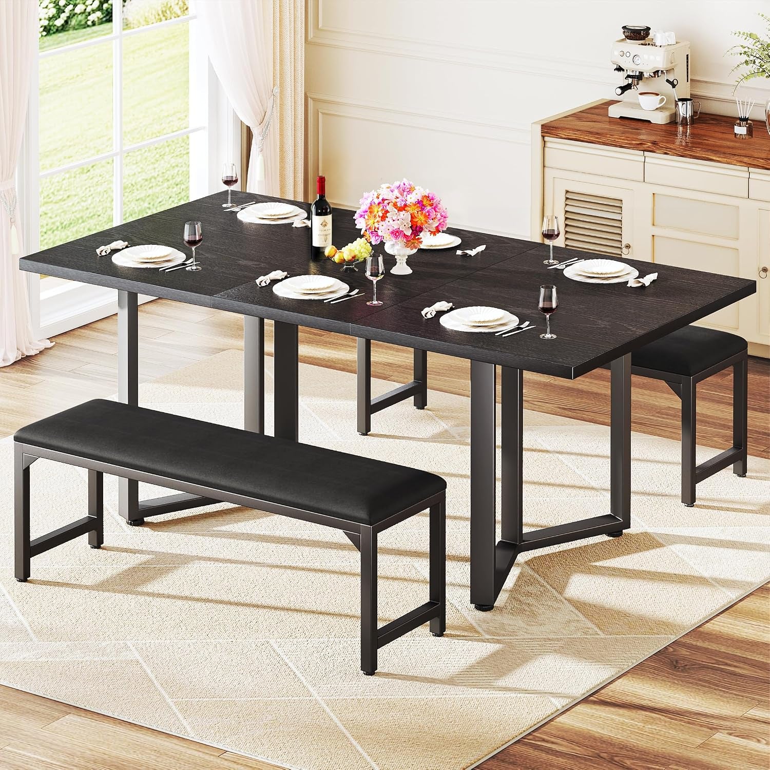 Black rectangular dining table with metal legs and two matching black benches set in a bright dining room.
